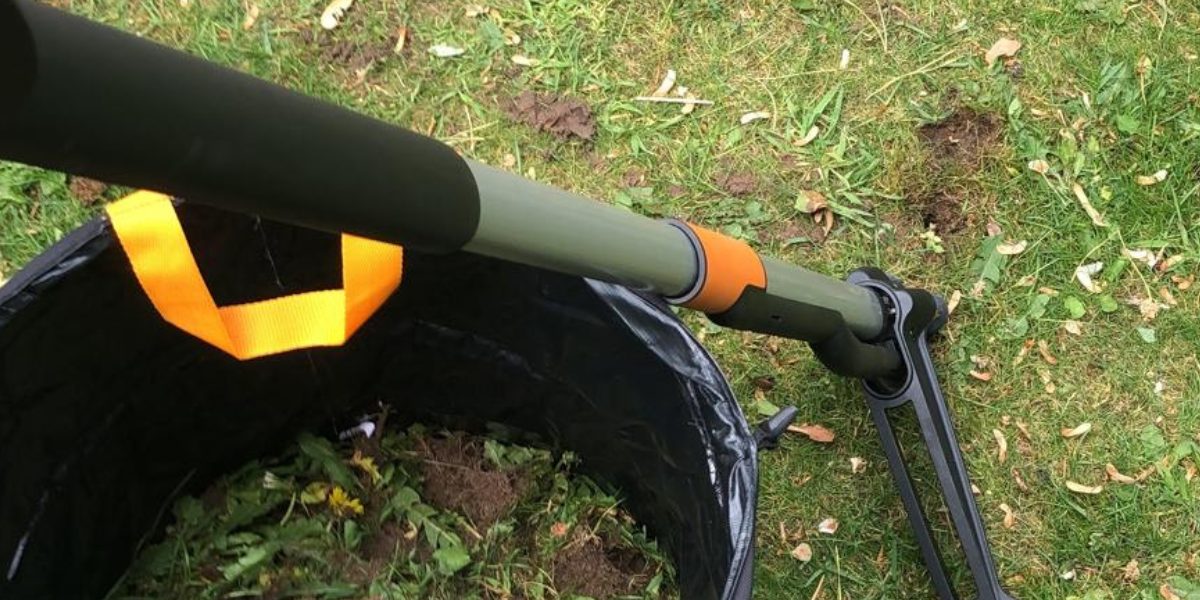 Penwortelsteker en een emmer met uitgestoken paardenbloemen in het gras